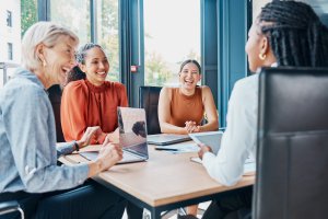 Laughing, planning business and women in a meeting for strategy, teamwork and a workforce team. Happy, office and diversity with people at work for a corporate collaboration and coworking together.
